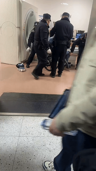 网友在医院里拍到一个坐着轮椅的犯人正在做CT检查。旁边有几个警察正在卸下他身上