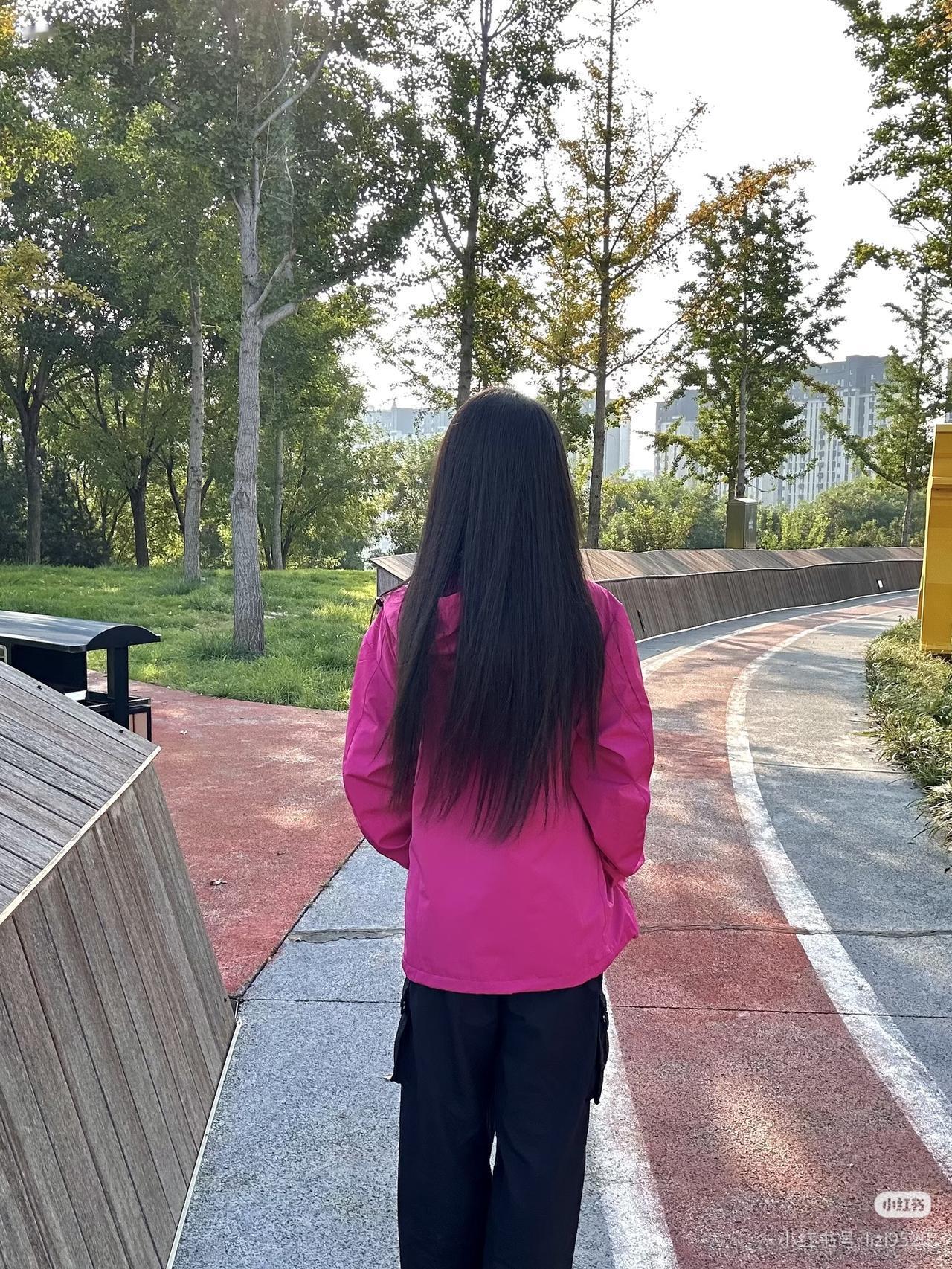 粉衣少女立林间，绿树掩映似画卷。