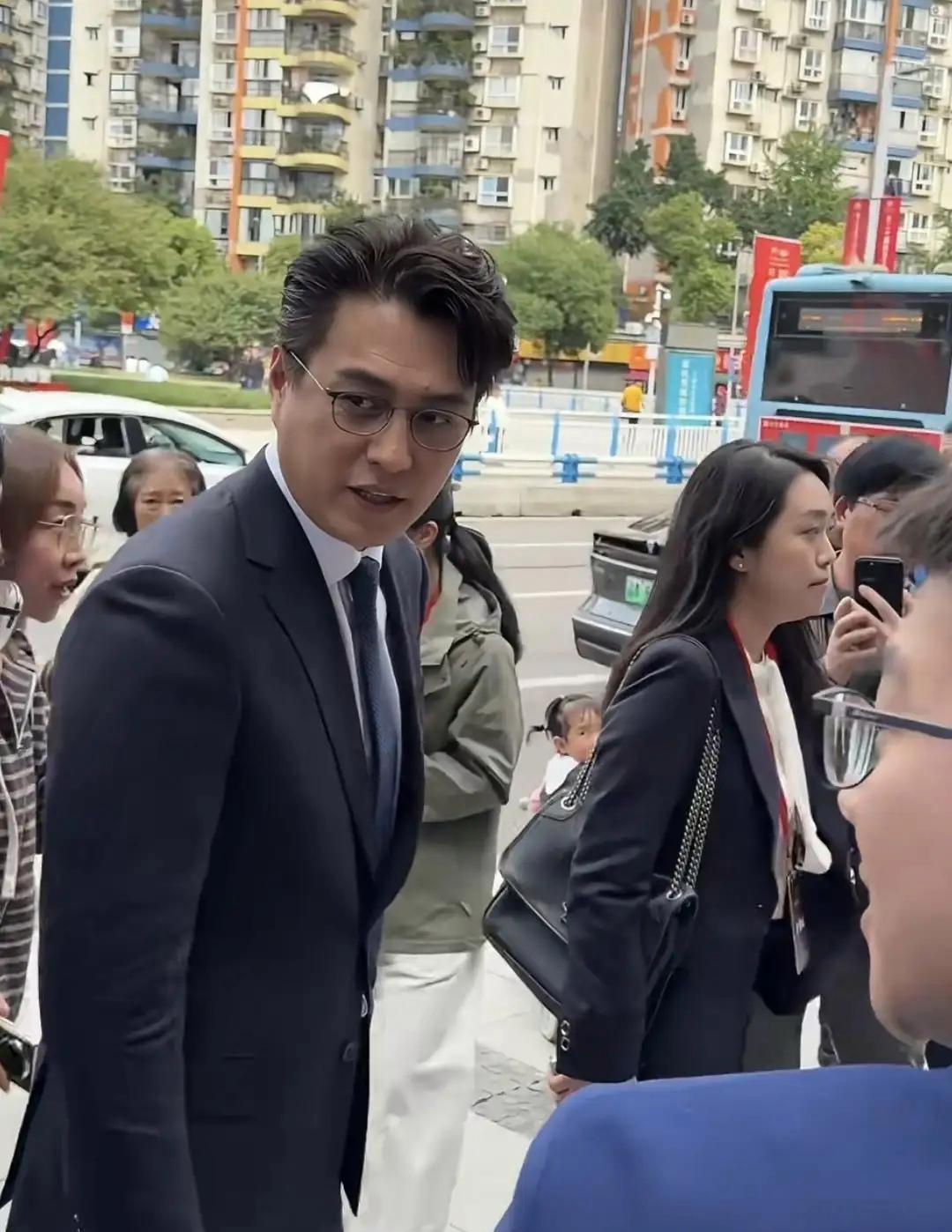 靳东穿西装戴金丝眼镜，站在重庆街头低着头，一句话没说，但所有人都知道他刚拿了个大