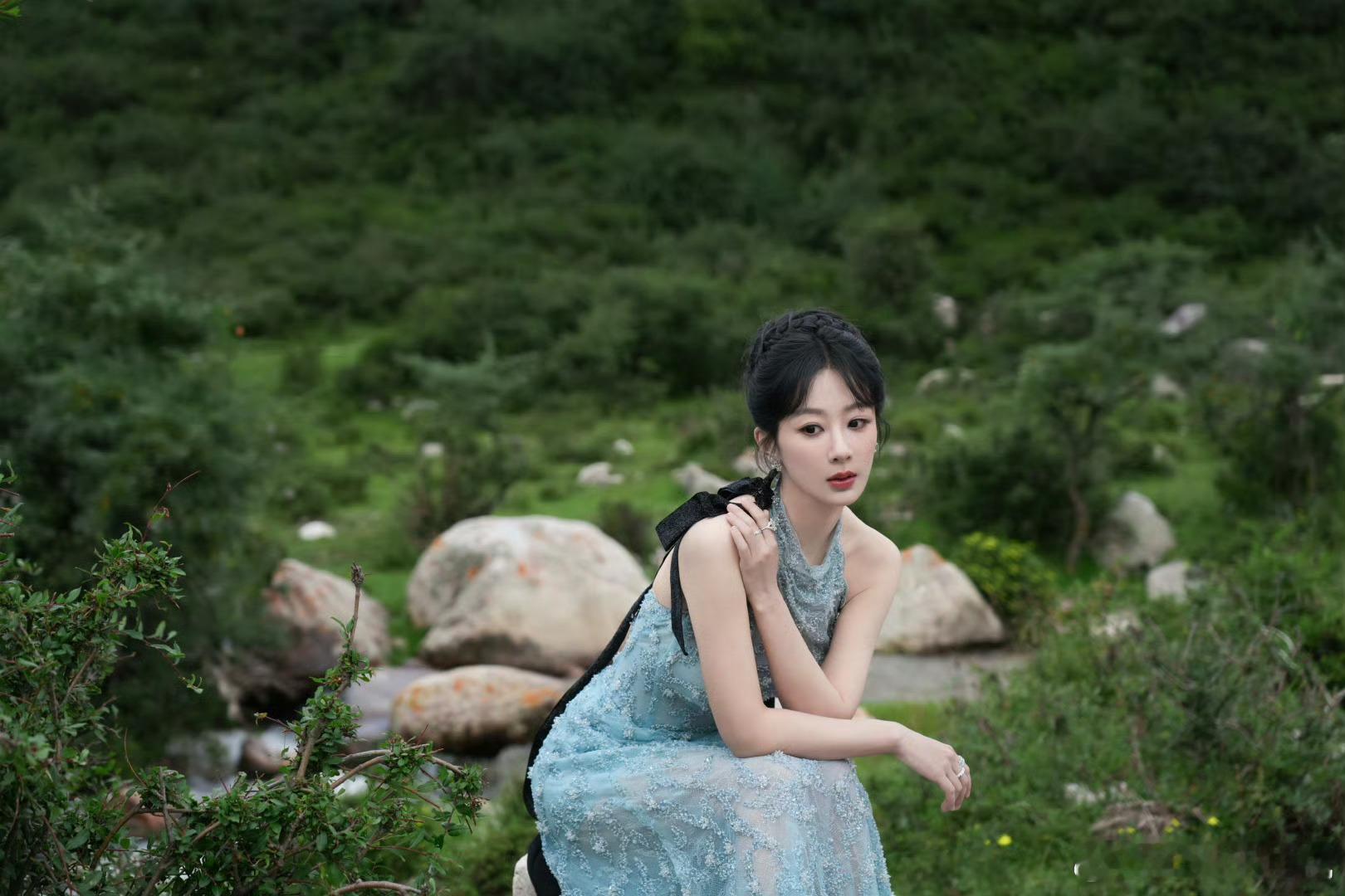 杨紫绿野葱茏间，杨紫身着蓝色蕾丝长裙翩然伫立。裙摆缀满细碎蕾丝如星光落