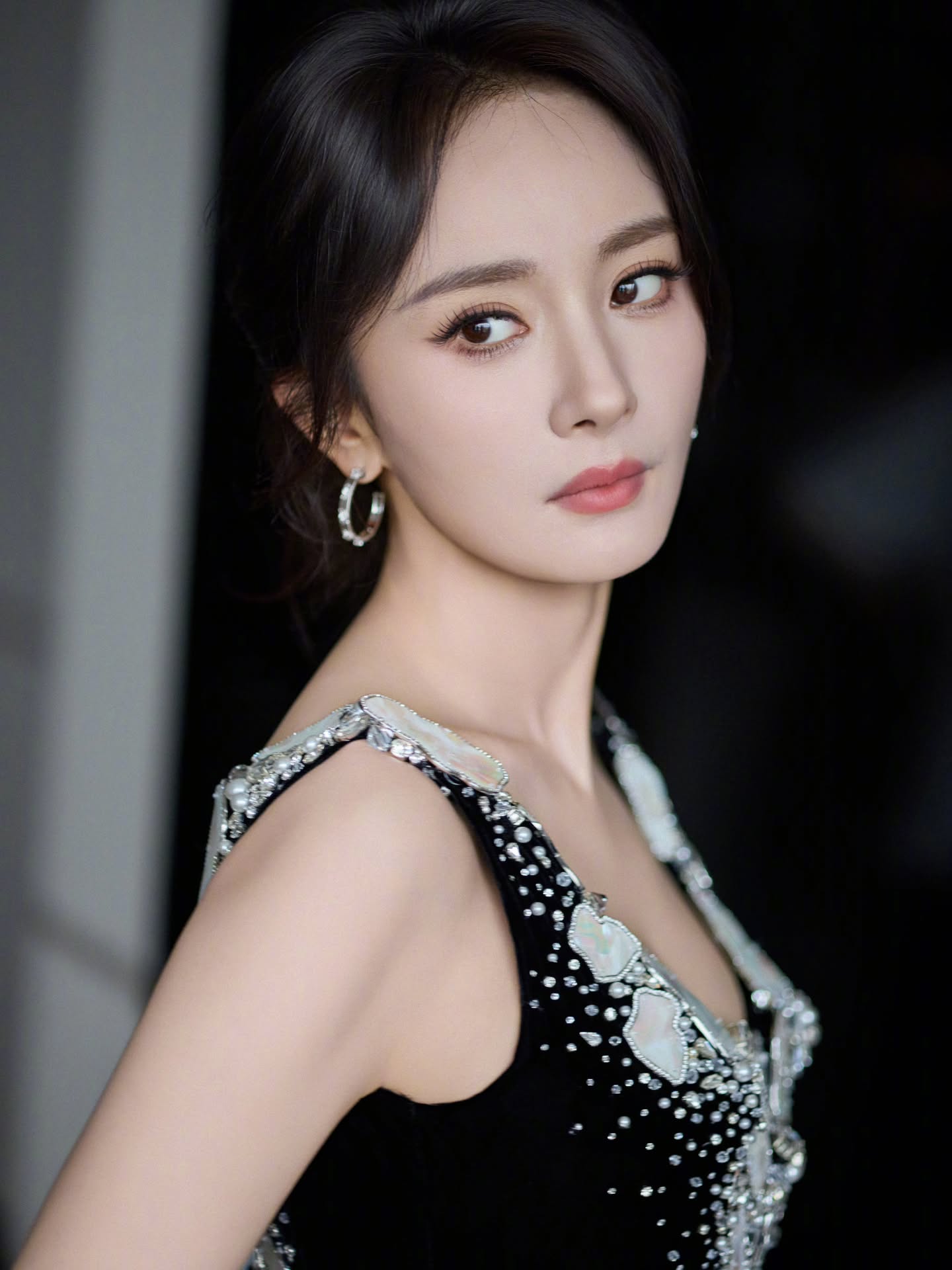 杨幂｜光影交错，冷艳女王杨幂一组时尚写真释出。她身着一袭黑色丝绒吊带长裙，肩带与领口处错落有致地镶嵌