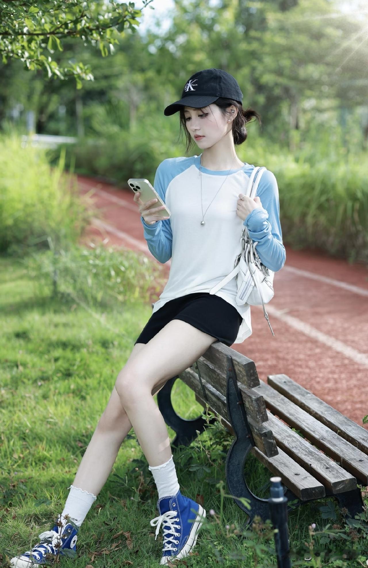 一个女孩坐在公园长椅上玩手机。