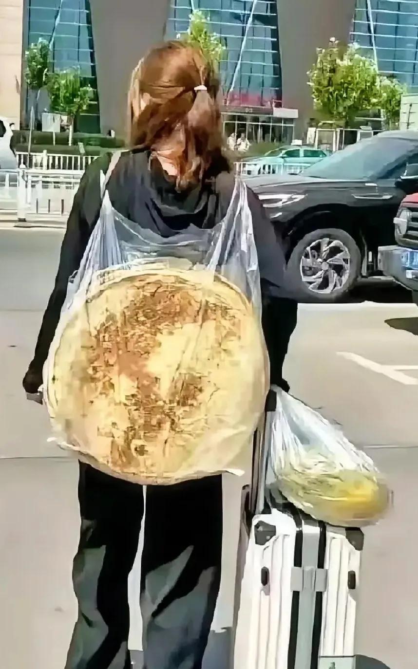 近日，一张新疆女孩背着两个大饼和一个哈密瓜走出深圳机场的照片，火爆全网，有人在夸