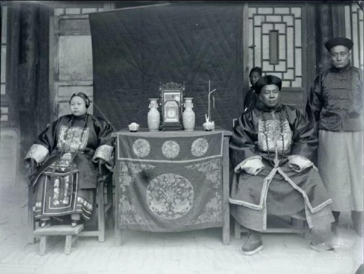 清代，一位官员与夫人的合影，旁边站着的男子是他的随从，背后的男子是他的家仆。照片