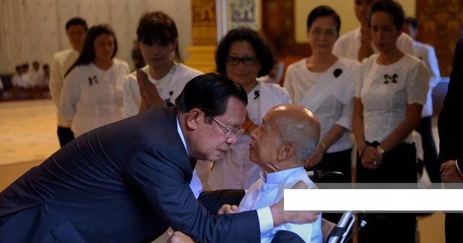 柬埔寨的拉那烈亲王坐在轮椅上，面对老对头洪森亲王，握紧拳头。而法国总统马克龙跟