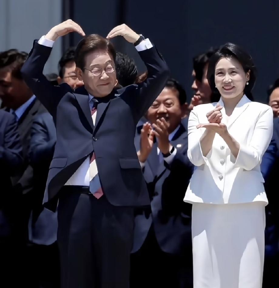 李在明经常就这么大庭广众下，不分场合，给他可爱的妻子比爱心。好歹也是韩国当家人