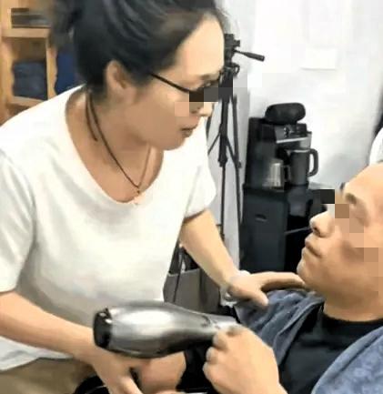 理发店里，老板娘举着吹风机正要给男子吹头，脚下一滑，直接嘴对嘴亲上了。老板娘没吭