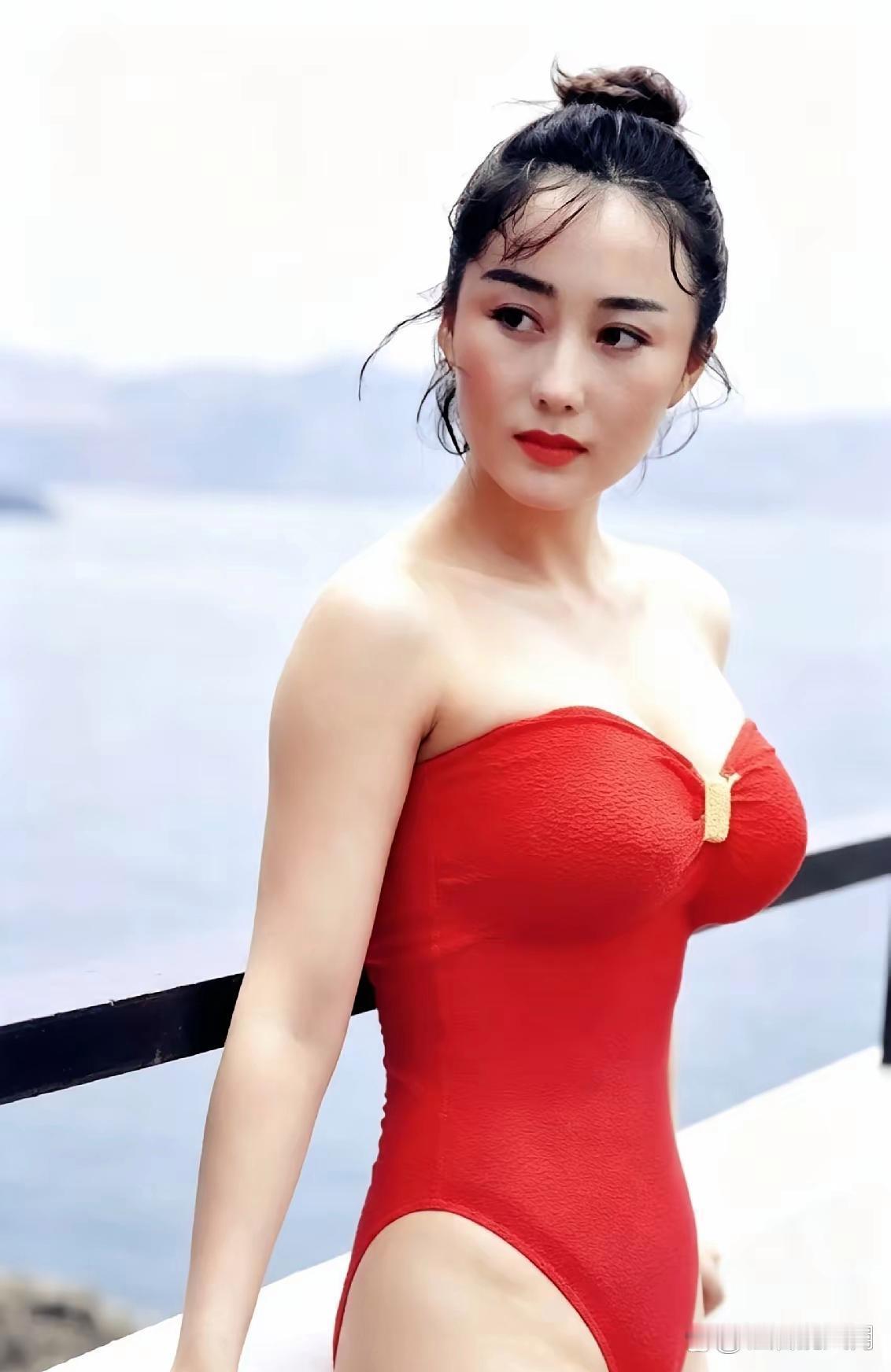 利智身着鲜亮正红抹胸泳衣，在临海露台边侧头回眸，风情绰约韵味十足，这玲珑曼妙的绝