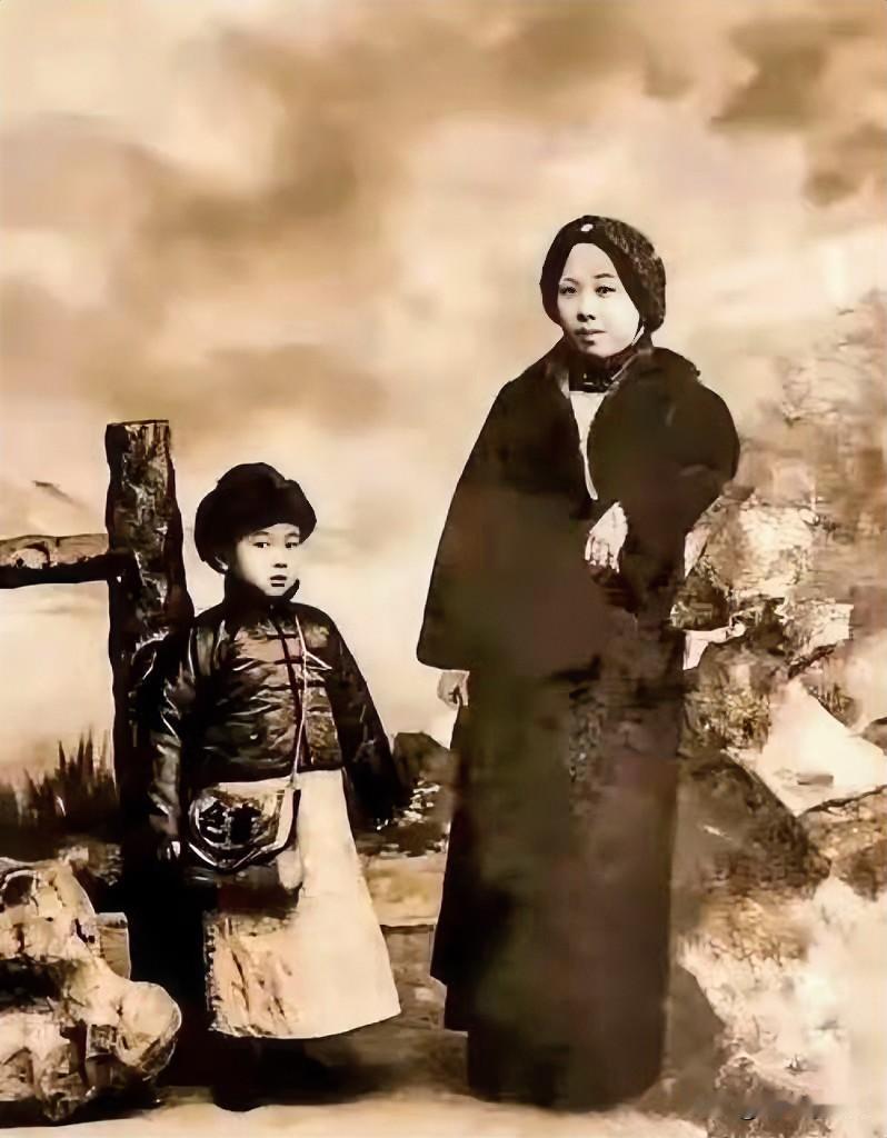 照片记录了1917年，6岁的钱学森与母亲章兰娟的合影。他身穿长袍马褂，头戴绒帽，
