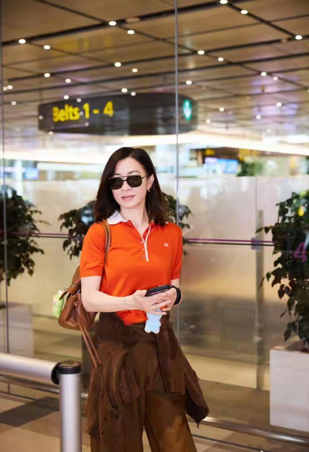 路人镜头下的佘诗曼状态惊艳！她身穿橘红Polo衫搭配棕色阔腿裤，腰间随意系着针织