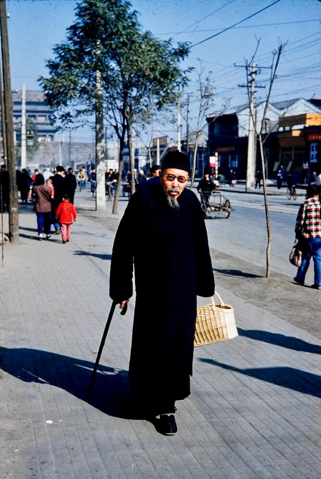 1959年的北京崇文门大街，一名拎着筐子逛街的老者。老者留着花白的胡子、穿着