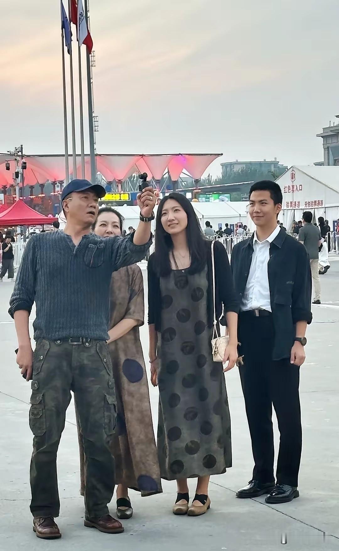 北京五棵松广场偶遇胡军一家，准备看音乐会。胡军穿深色针织衫配迷彩裤，身形硬朗，依