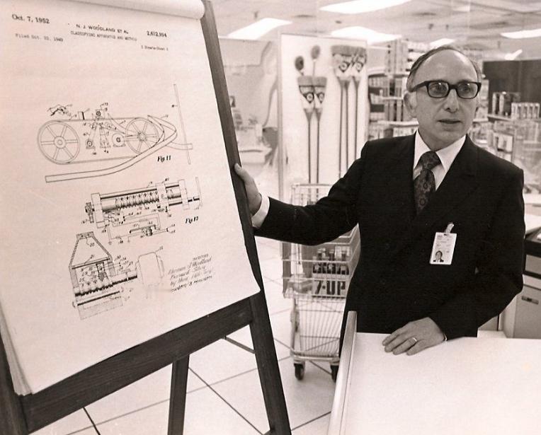 1948年，迈阿密海滩。诺曼·伍德兰蹲在沙子里，伸出四根手指划出一道道纹路。他