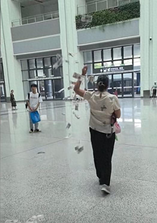 广州白云高铁站内，一位女子在地铁和高铁连接通道，边走边从布袋掏出大把1元、5元零