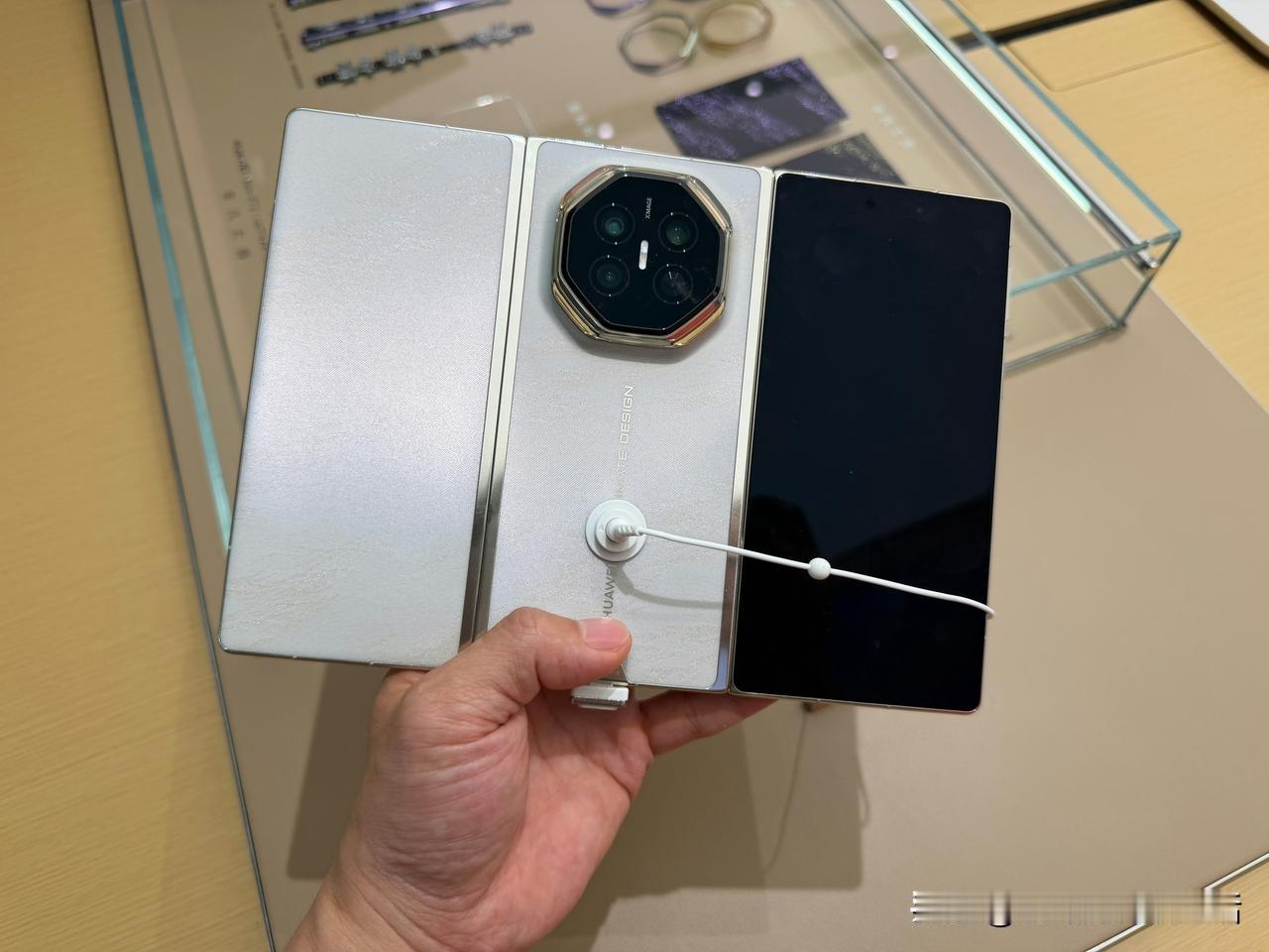 华为门店最近多了个挺特别的展柜：两万块的三折叠整机摆在台面上，随便上手翻；旁边玻