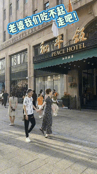 上海和平饭店门口，一对夫妻牵手路过。老公看着气派的大楼，拉着老婆小声说：老婆，