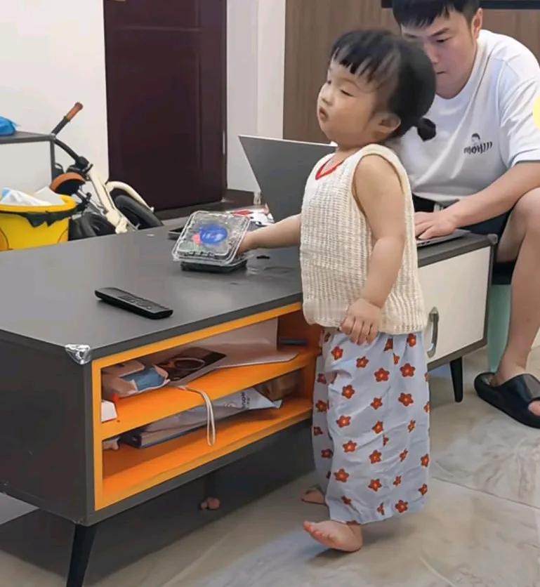 男子忙着在电脑上工作，被女儿喂了一颗沾着洗脚水的蓝莓，女儿从蓝莓盒里拿起一个蓝