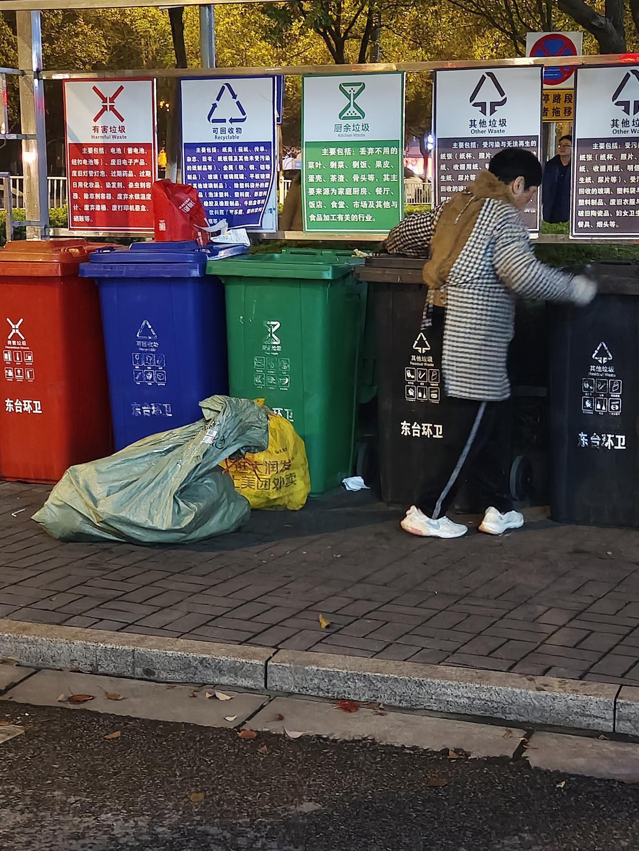 晚上20点半了，路遇一景：一中年妇女守着几个垃圾筒，把扔在筒内的垃圾袋挨个扒开，