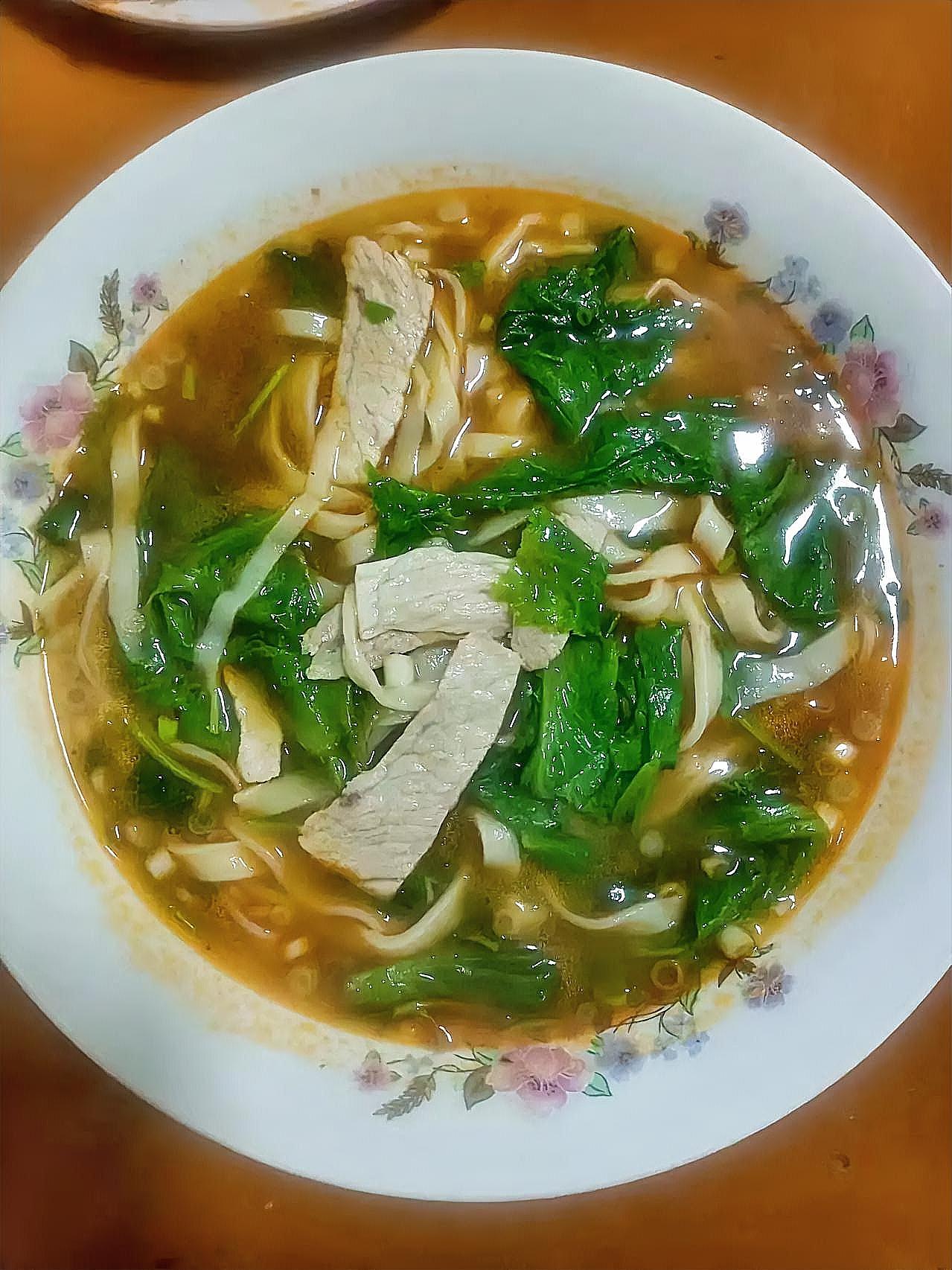 这碗家常面看着就暖乎乎的！手擀的面条筋道又爽滑，浸在金黄的汤里，几片扎实的瘦肉铺