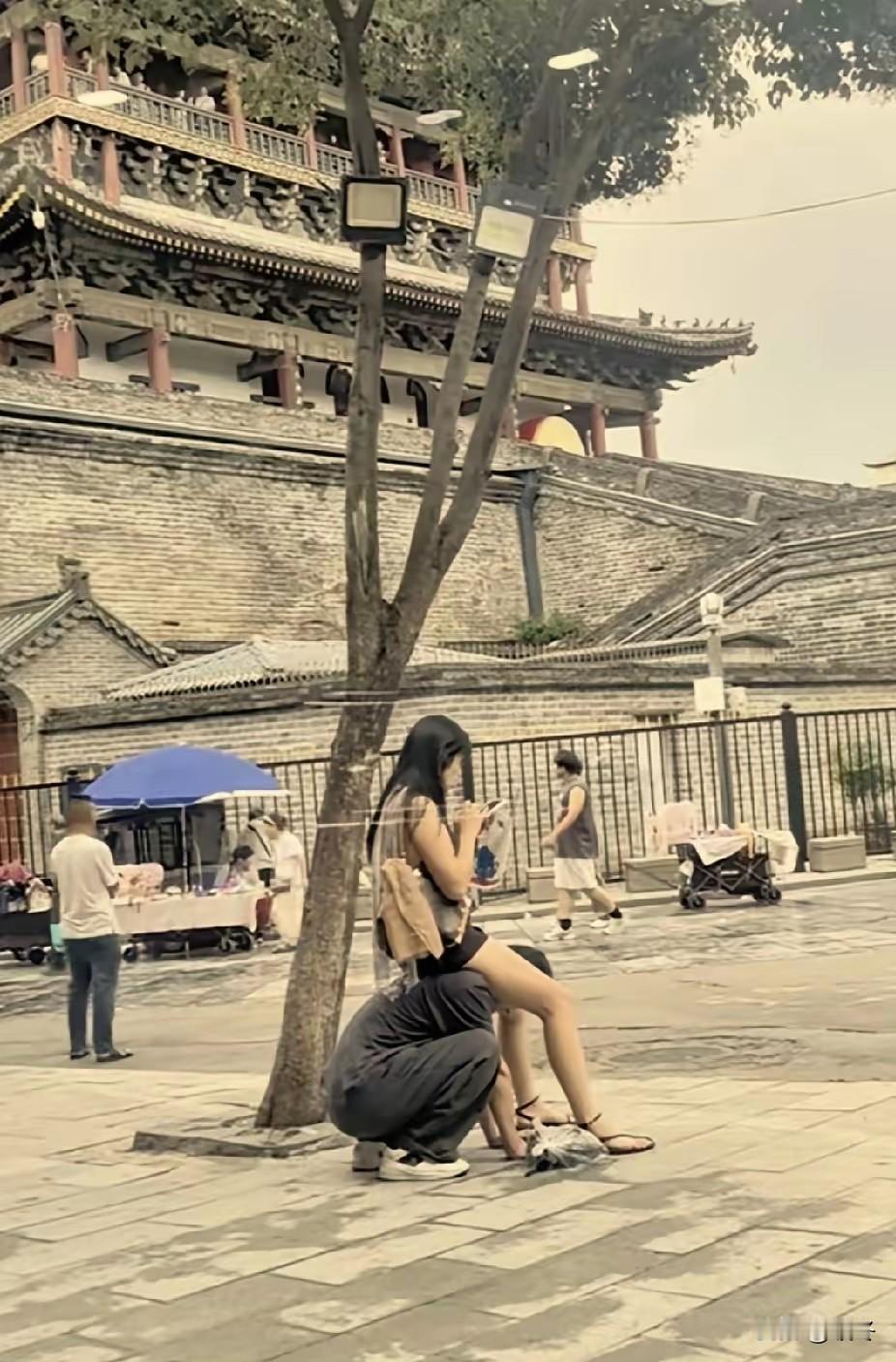 街头当众把男友当坐骑，男生趴在地上充当代步工具，女生坐在肩头只顾低头刷手机。不少