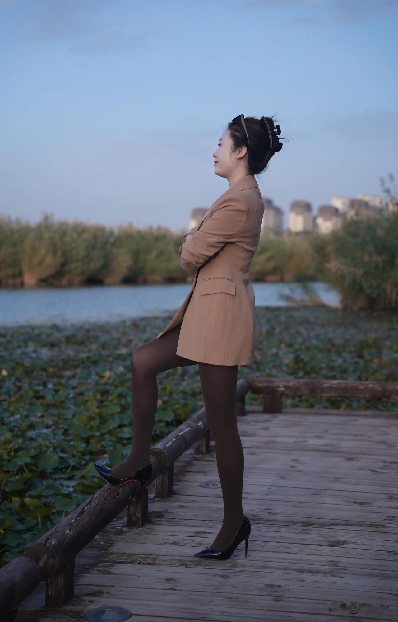 一个女人站在湖边的木栈道上。
