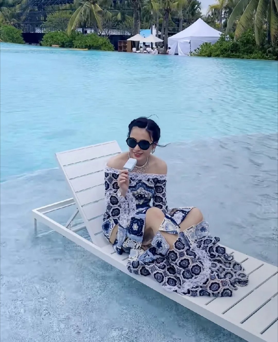 香港富婆甘比晒出酒店泳池边写真，身着亲手钩织的抹胸连衣裙，在摄影师指导下摆着po