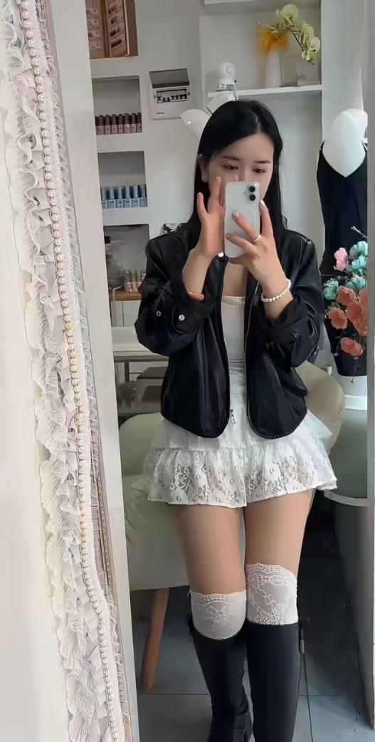 女孩穿短裙对着镜子拍照。