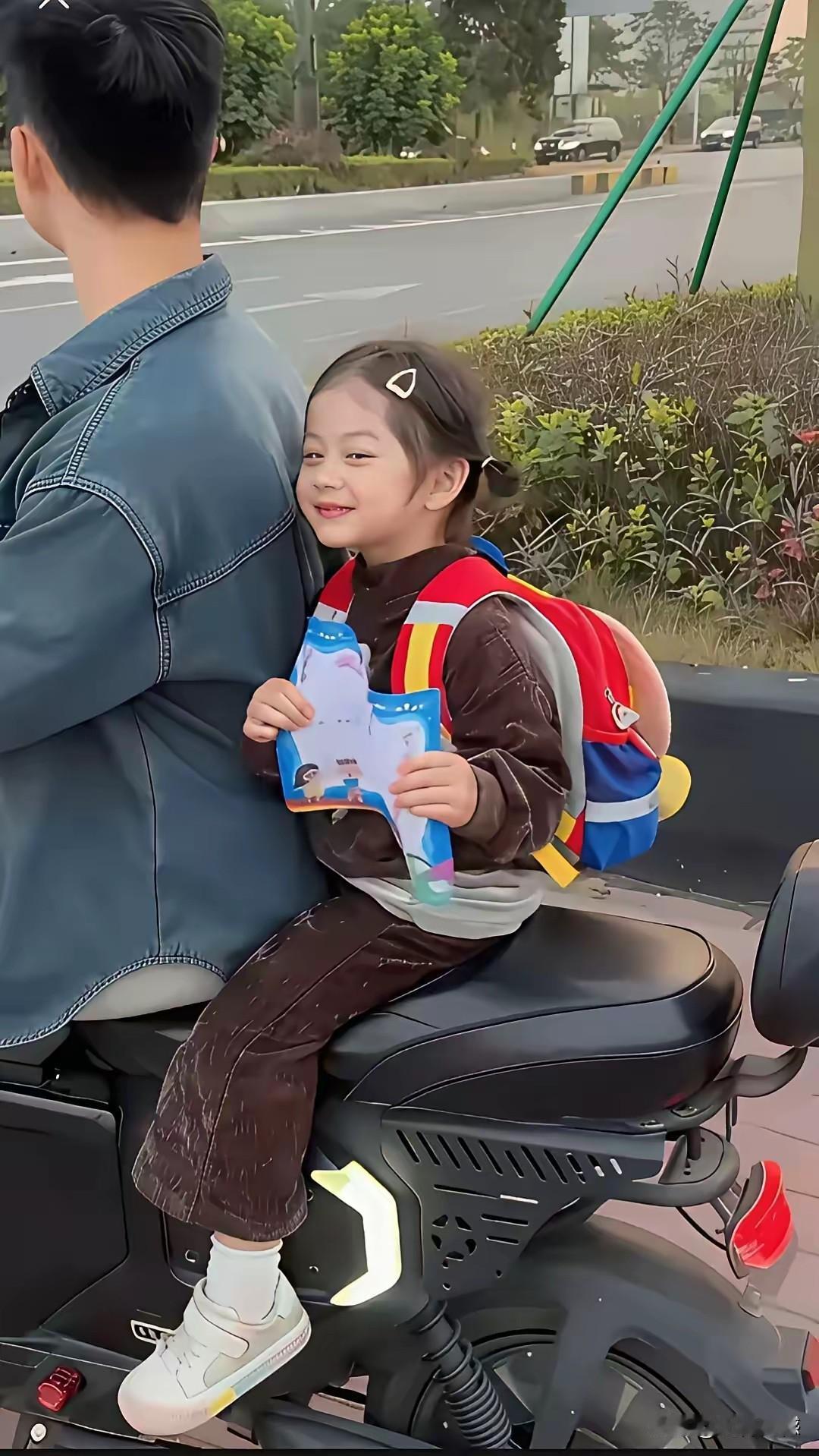 孩子得了个奖状，非常的开心，坐在爸爸的摩托车上，也没有忘记向外人展示，这是个非常