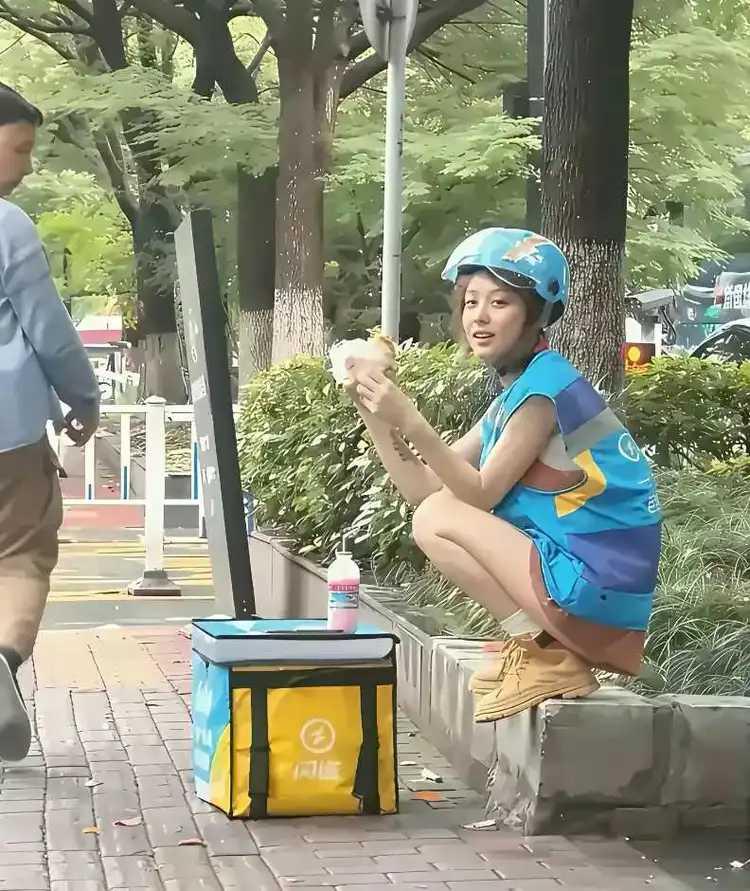 中午时分，路边骄阳似火。一位外卖姑娘正蹲在石阶上，吃着手中的面包。她究竟送了多