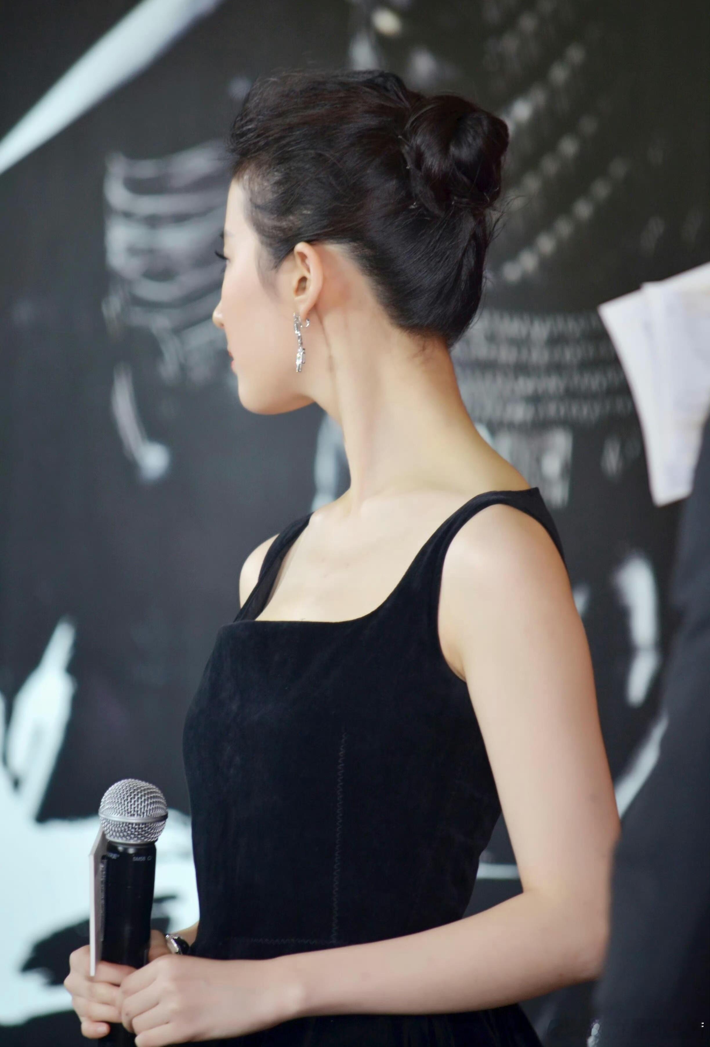 刘亦菲身着黑色丝绒方领吊带裙，丝绒的哑光质感在灯光下细腻变化，既沉稳又华丽。方领