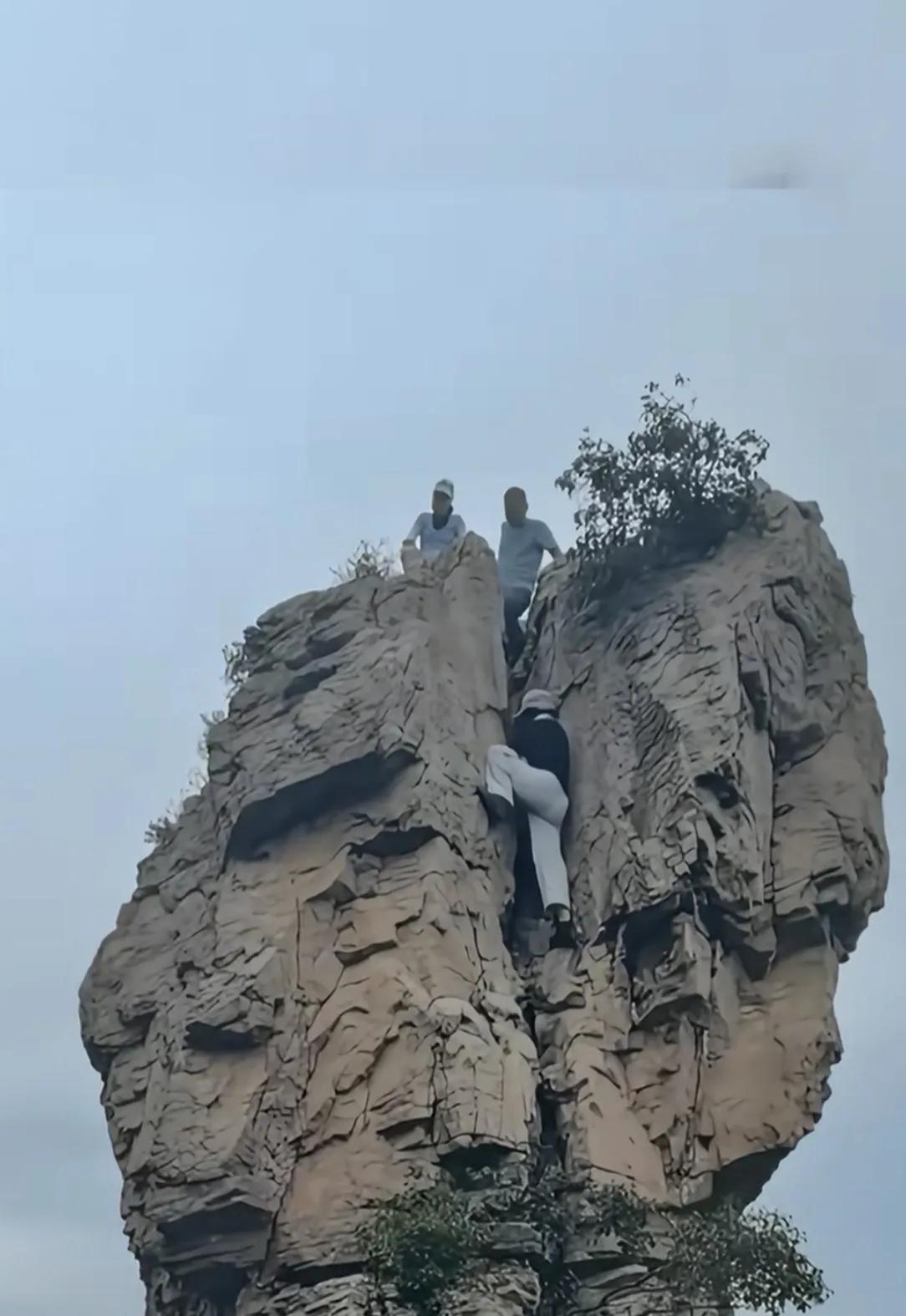 看着都捏一把冷汗！几位游客徒手攀爬高耸的危岩，崖壁陡峭没有防护措施。登山游玩千万