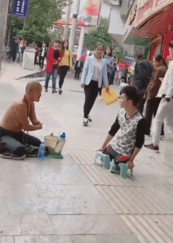 一失去双手的男子在街头乞讨，这时，一个无腿的小伙双手撑着凳子艰难地挪了过来。他从