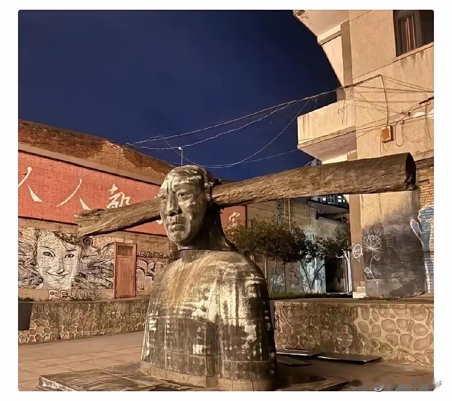 这雕塑是要给谁添堵？！好家伙，一根粗木梁从人像脑袋穿进去，直挺挺地戳出来，远