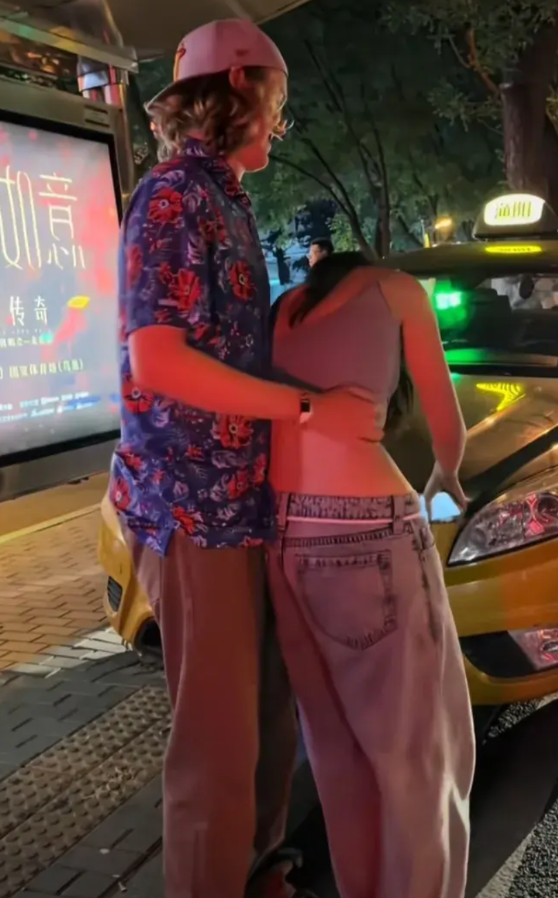北京三里屯夜里灯火辉煌，一辆出租车停在马路边上等着一对情侣上车，男情侣是一名外国
