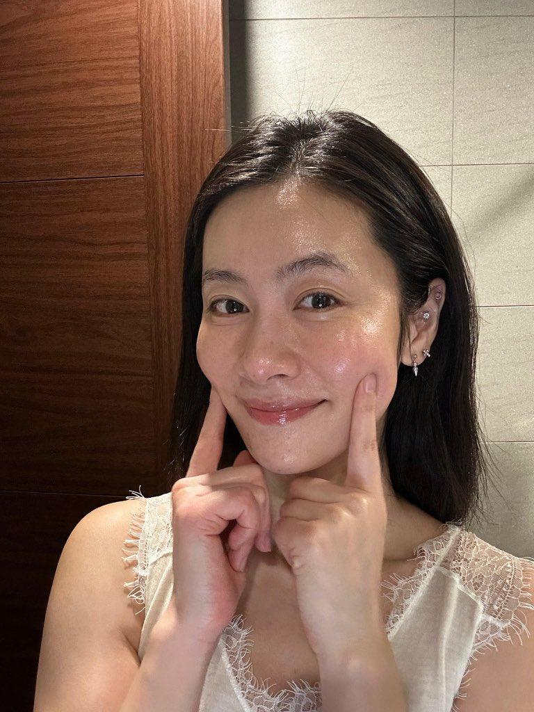 35岁阿姨的自拍照，身穿薄纱蕾丝上衣，在浴室镜子前摆出略带微笑、捏着脸颊的姿势。