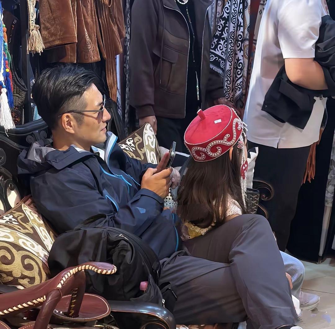 严屹宽和女儿在新疆旅游，他身穿蓝色连帽外套，白色旅游鞋，背着背包，头发乌黑浓密，