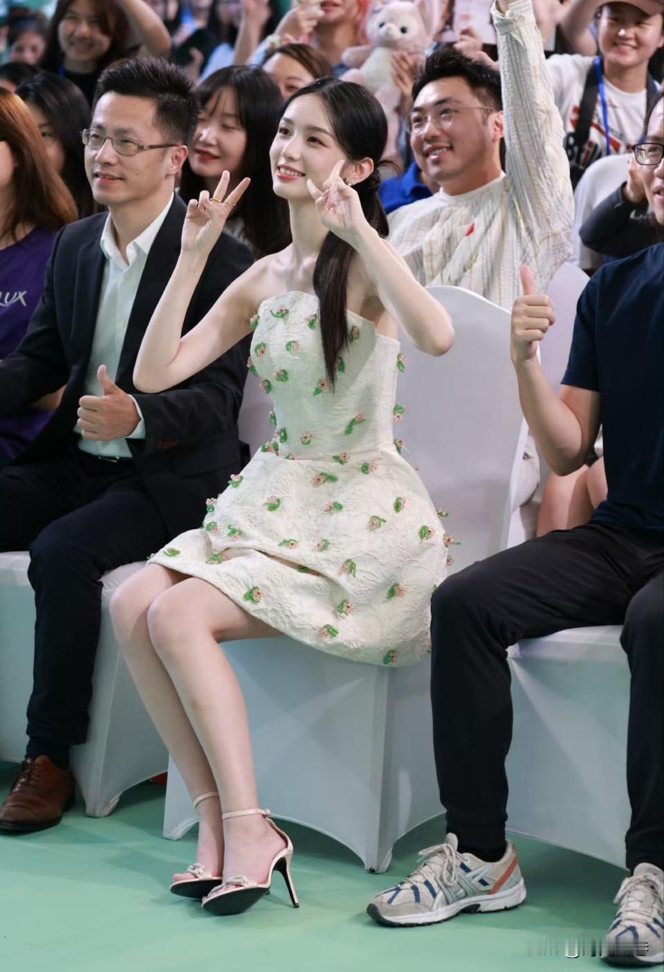 周也活动现场美照，笑容清新甜美，小动作优雅可爱。印花连衣短裙搭配精致高跟凉鞋。清
