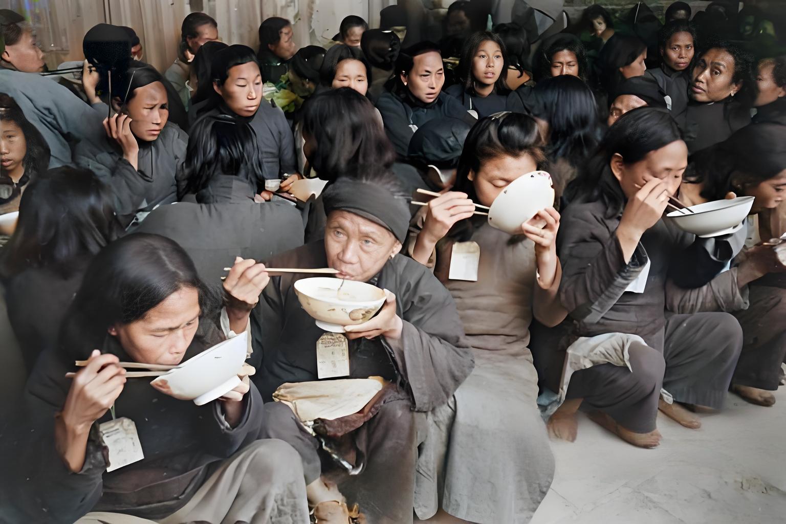 这是民国时期湖南饥荒场景的照片，众多灾民席地而坐，捧着碗用筷进食，身上挂着标识牌
