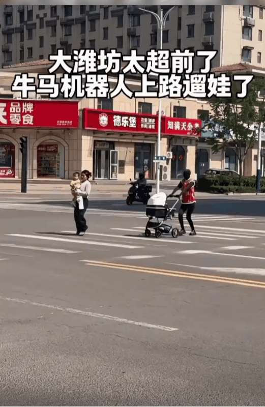 山东潍坊一女子在街上遛娃逛街。在她的身边竟然还跟着一个推着婴儿车的机器人？不