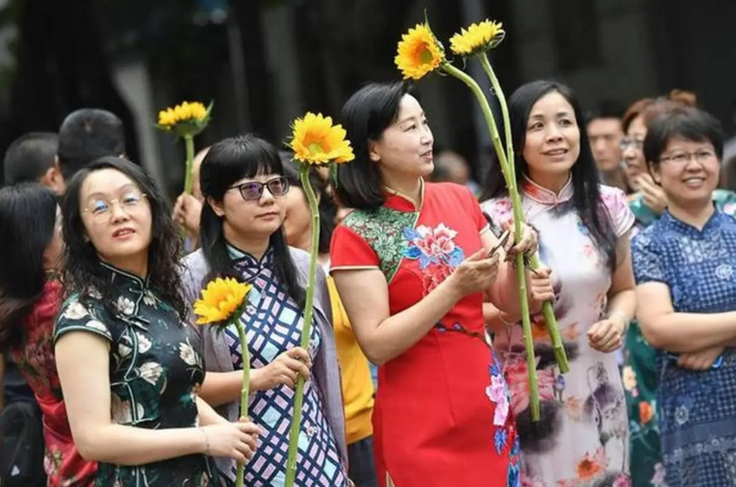 今天高考，考场内比拼，高场外也在比拼，比的是大妈们怪招奇出。穿旗袍的，拿向日葵的