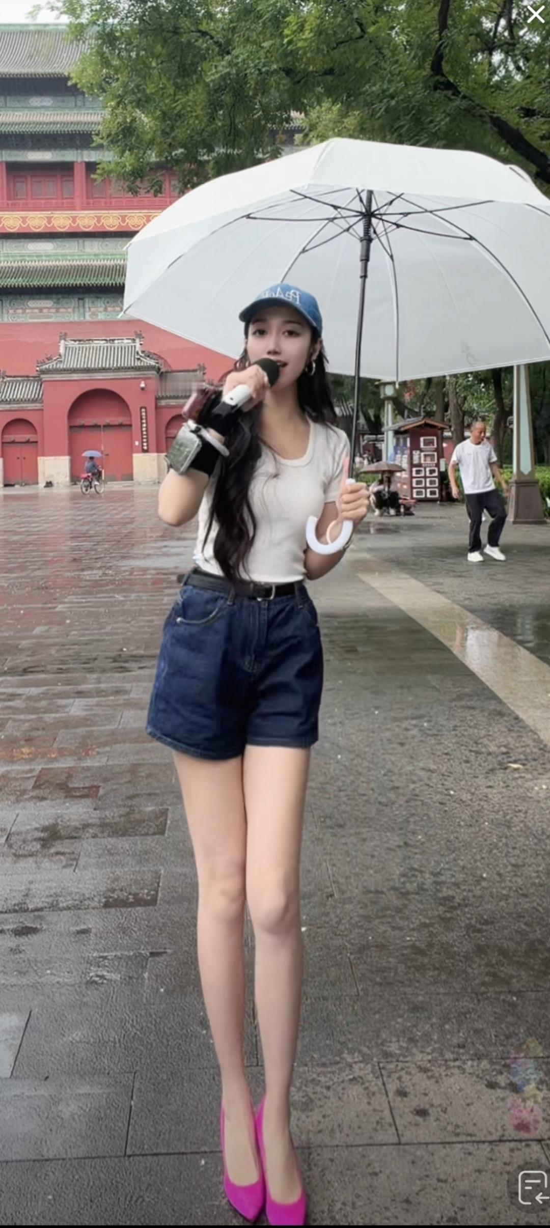 下雨天，美女撑伞在户外唱歌。