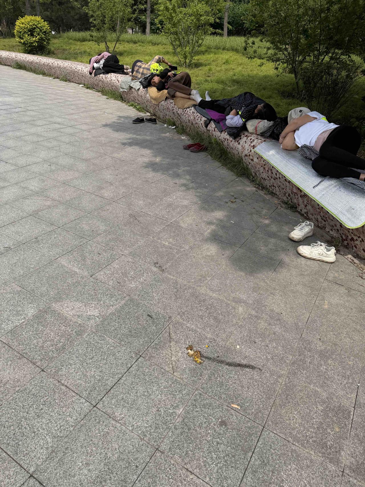 几个工人在长椅上睡觉，鞋子散落在地。大夏天还是很辛苦的！夜里的建筑工地打工小憩