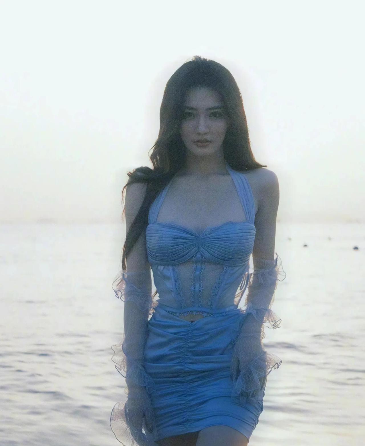 海边的张萌美到开挂！一袭淡蓝裙装勾勒傲人曲线，发丝随海风轻舞，抬手、侧颜，每帧都