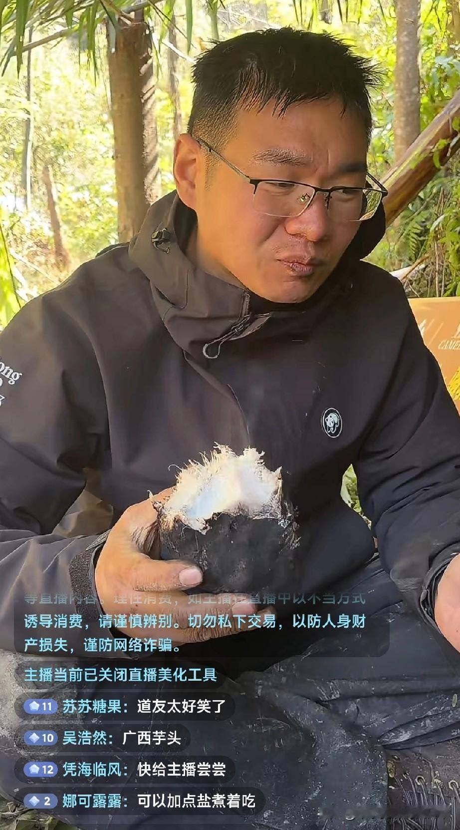 荒野求生道友抱芋头狂啃!七星山荒野赛直播里，这位“道友”蹲在草棚下抱着个黑