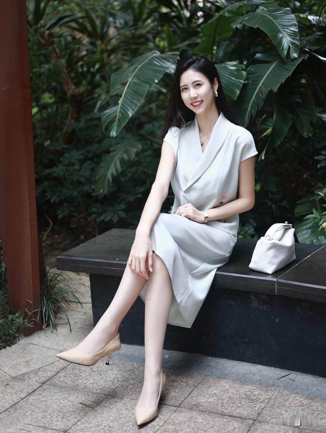 如何穿搭显得淑女一点优雅坐于绿意盎然中，白色连衣裙与高跟鞋相得益彰，尽显都市女性