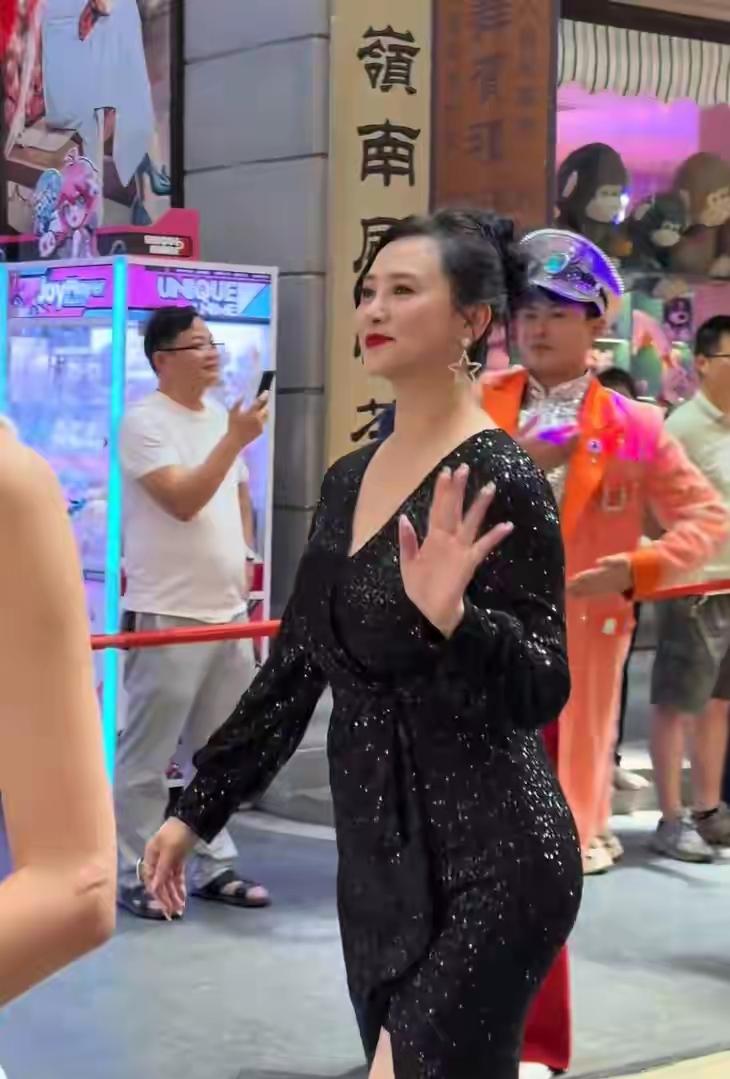 58岁翁虹惊艳亮相某景区，与地方演出人员一起跳舞，穿黑色亮片高开叉裙长裙，依旧是