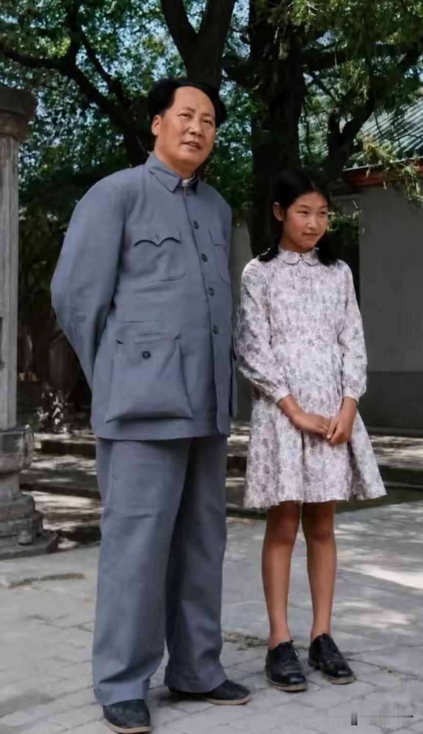 这是红色影视剧中的场景，演员饰演毛泽东同志，与饰演革命年代少女的小演员并肩站立，