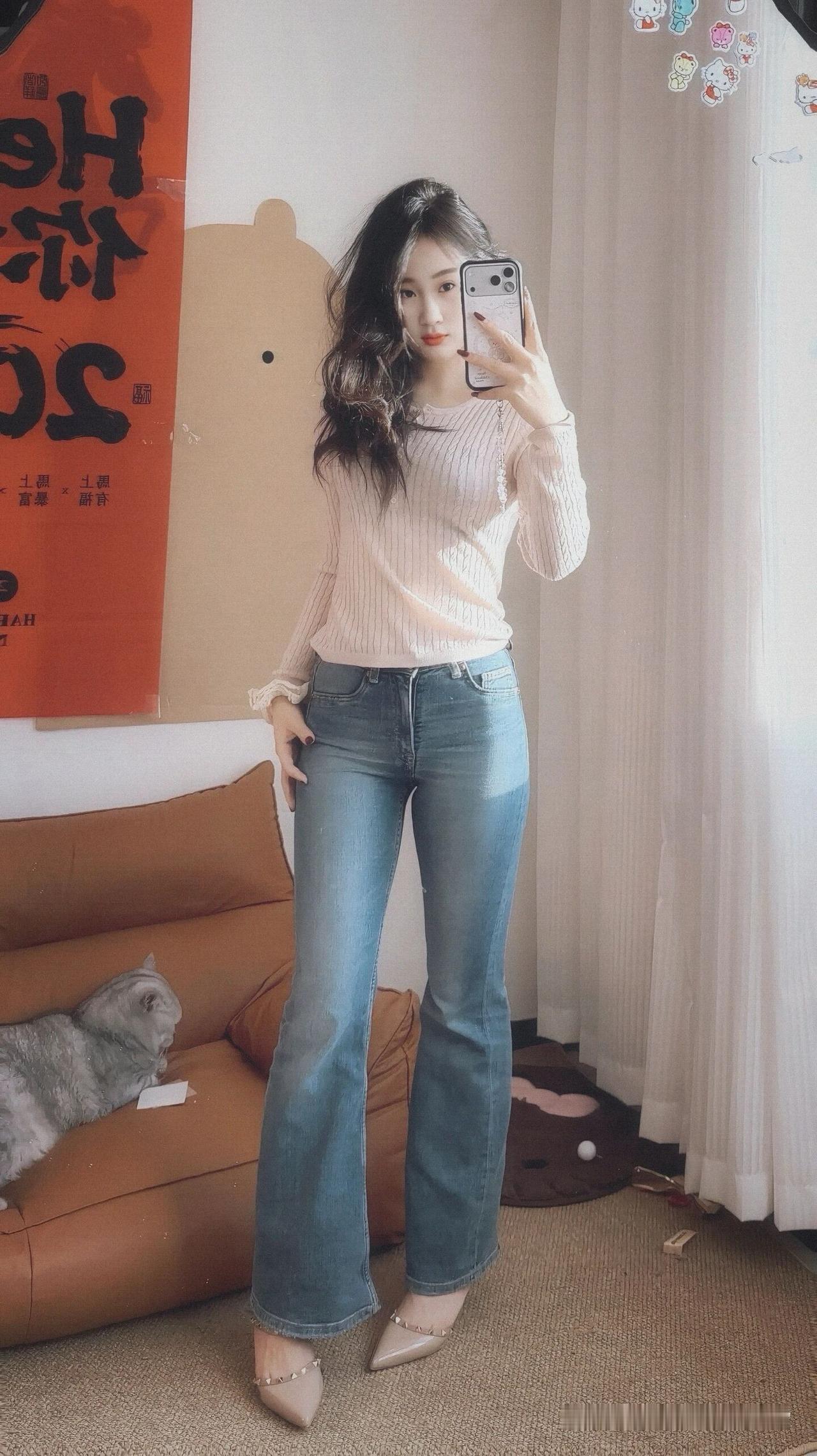 女孩自拍，穿宽松牛仔裤，背景有猫。