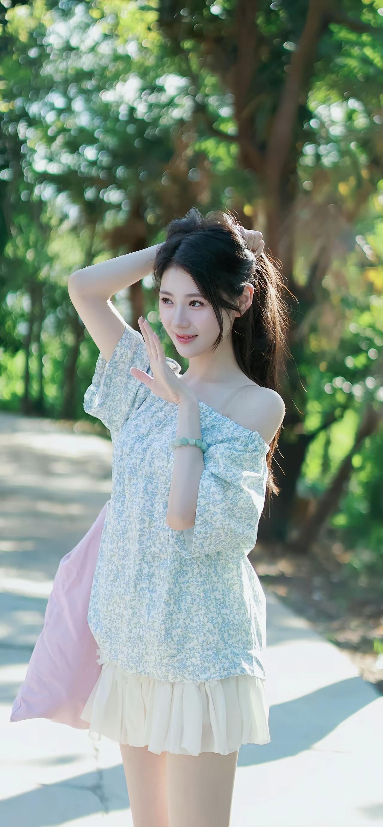 一个女孩在阳光明媚的公园里摆姿势。美女姿势照温柔风少女拍照公园拍照动作