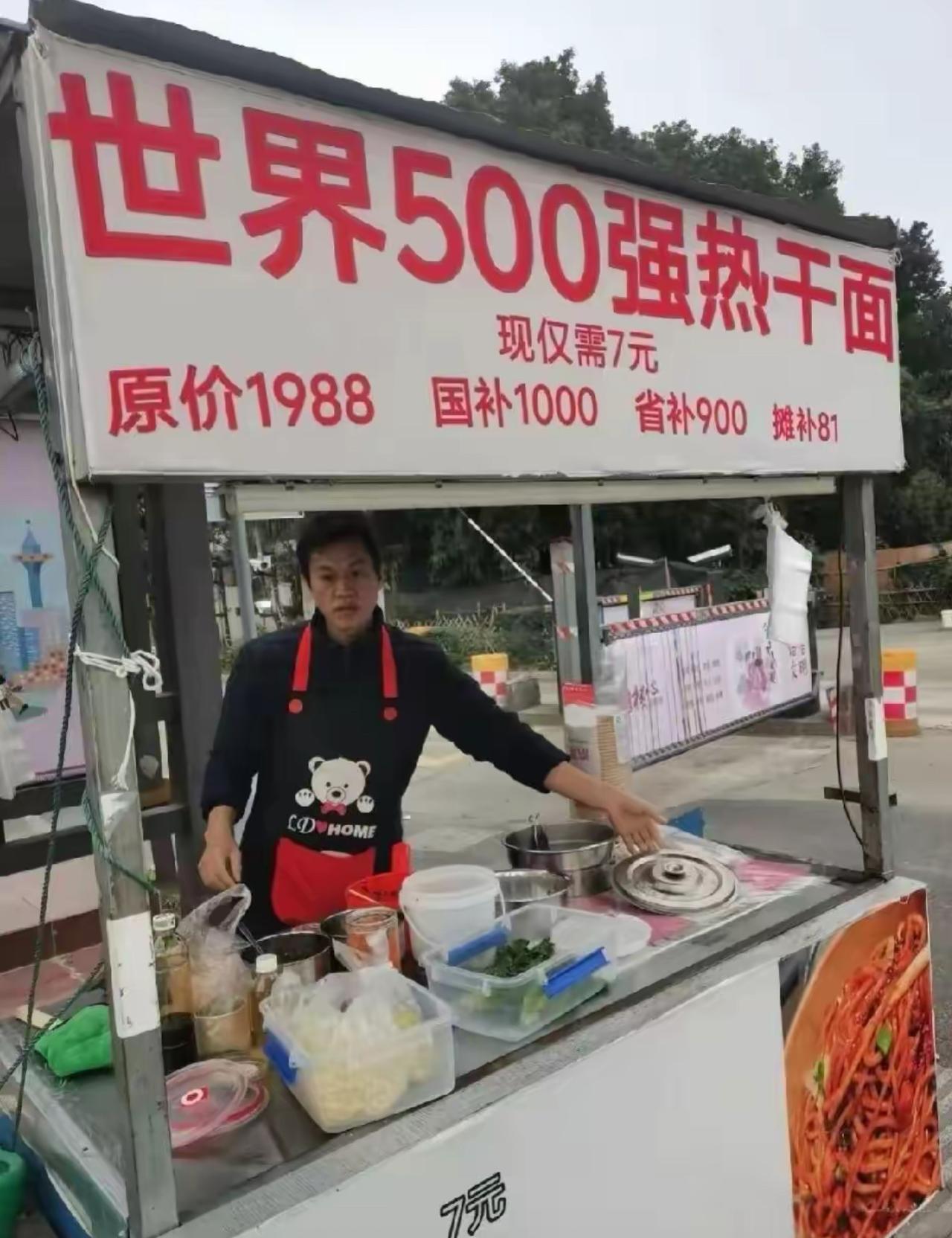 路边一个不起眼的小吃摊，招牌直接打出世界500强热干面的名头，噱头拉满。一碗